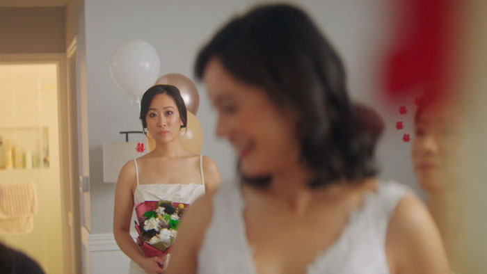 Alex (Lois Shih) watches on, bouquet in hand, before the ceremony in Big Day.