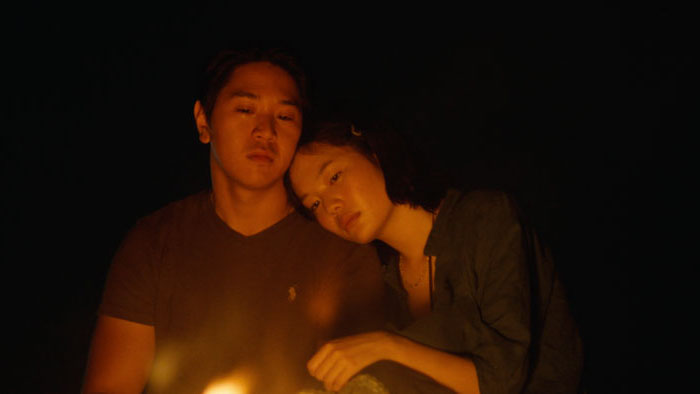 Jinna (Michelle Jones Lee) rests against Alex (Arnold Setiadi) by candlelight in Heading to the East.