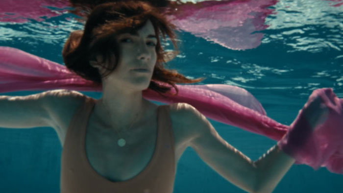 Marga (Maria Bata) floats underwater with a pink scarf in In the Deep.