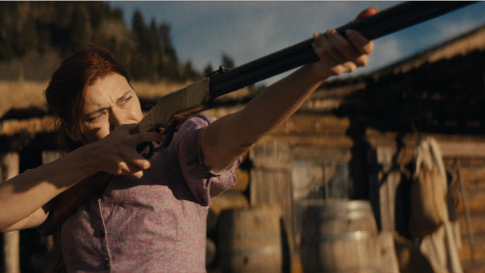 Charlotte (Kerry O'Malley) raises a rifle to defend her homestead in Last Stand at Butte City.