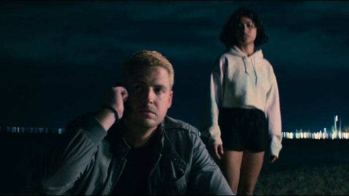 Sonny (Mason Jendel) and Nyah (Sahara Ale) stand on a nighttime beach in Nowhere Fast.