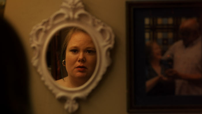 Trish (Jen Ponton) stares into an ornate mirror in Resentment.