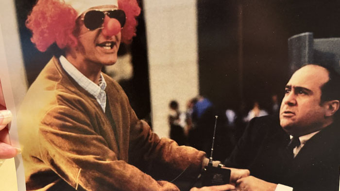Judge Reinhold, disguised in a red clown wig, hands off a two-way radio in a scene from Ruthless People.
