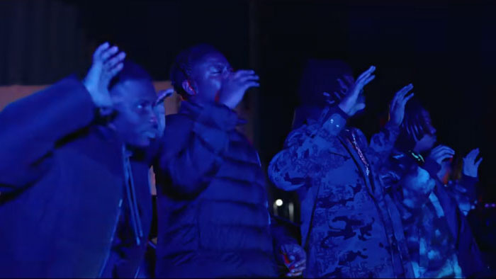 A group of young men clap and react under blue light at night in Splash City.