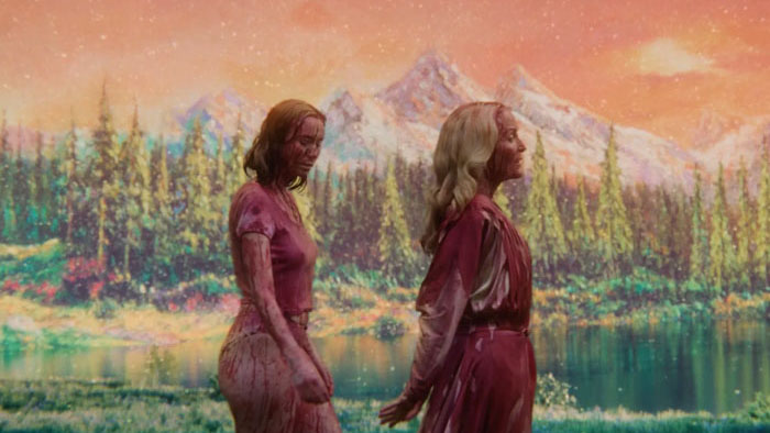 Blood-covered Kris (Hannah Einbinder) and Billy Presley (Gillian Anderson) walk beside a lake in Teenage Sex and Death at Camp Miasma.