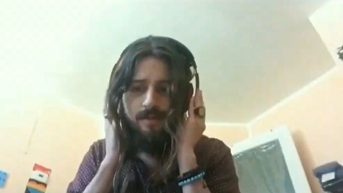 Misi (Mikomi) adjusts his headphones during a video diary entry in Waterfall Colors.