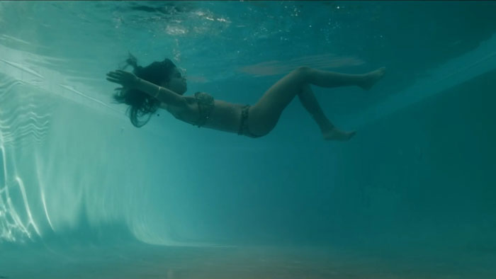 Indy (Siena Agudong) floats underwater in a pool during a dream sequence in You're Dead to Me.
