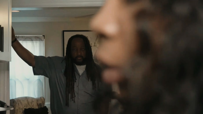 Kimmie (Symerah Scott) stands at a mirror as a blurred Lance Turner (Toda Moyer) looms nearby in Never Leaving.
