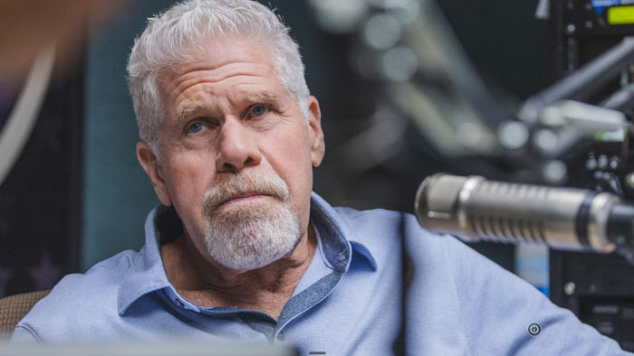 Dalton Kirby (Ron Perlman) sits at a radio microphone in Come with Me.