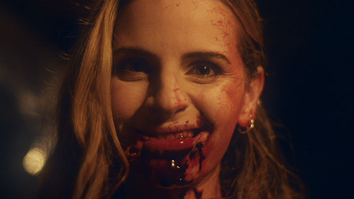 Nicole (Kristen Kaster) smiles with blood on her mouth in a scene from Hy3na.