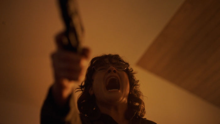 Patricia (Cheyenne Perez) screams while holding a gun in a tense scene from Influence.