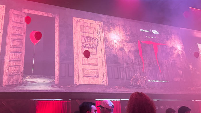 Pennywise (Bill Skarsgård) grins on screen surrounded by masses of red balloons at the IT in Shared Reality premiere.