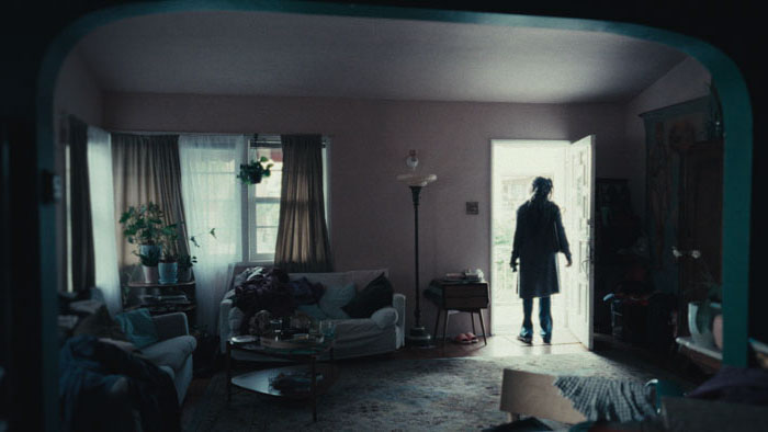 Carmen (Karole Foreman) stands in a doorway lit from outside in Light Bunny.