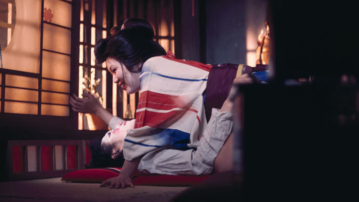 Minako Kiyomiya (Junko Miyashita) in an intimate embrace on a tatami floor in The Watcher in the Attic.